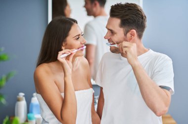 Banyoda diş fırçalayan mutlu genç çiftin portresi