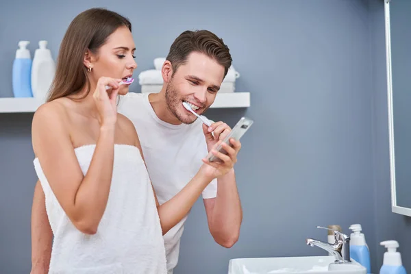 Retrato de feliz casal jovem escovando dentes no banheiro — Fotografia de Stock