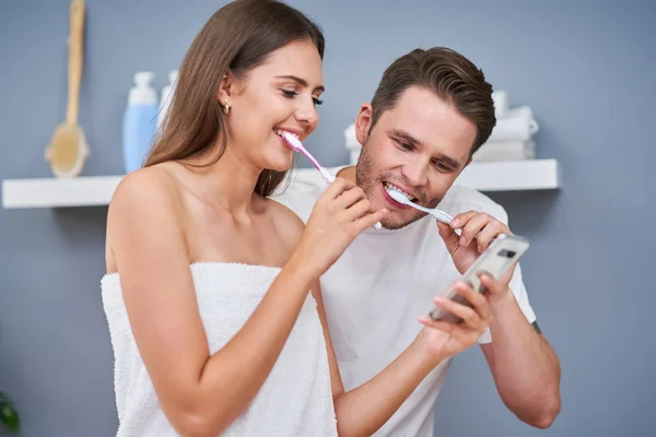Banyoda diş fırçalayan mutlu genç çiftin portresi — Stok fotoğraf