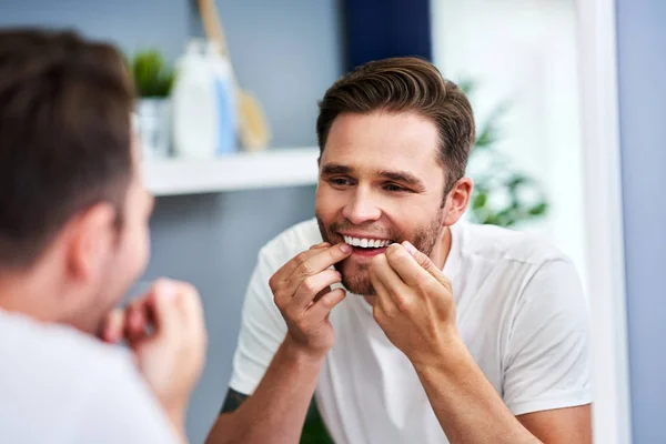 Felnőtt ember fogselyem fogak a fürdőszobában — Stock Fotó