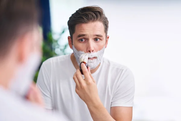 Портрет взрослого мужчины, бреющегося в ванной комнате — стоковое фото