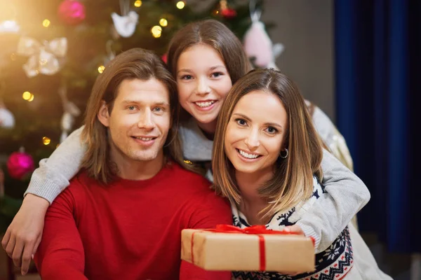 Mooie familie met cadeautjes over kerstboom — Stockfoto