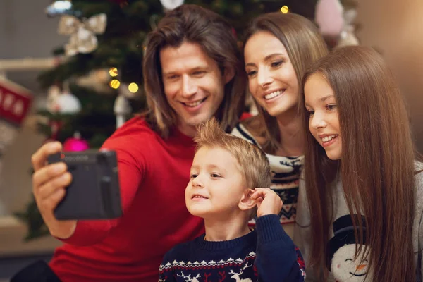 Hermosa familia celebrando la Navidad en casa y tomando fotos instantáneas — Foto de Stock