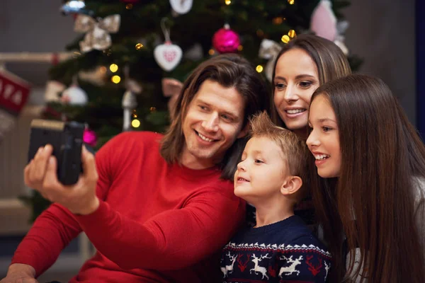 Hermosa familia celebrando la Navidad en casa y tomando fotos instantáneas —  Fotos de Stock