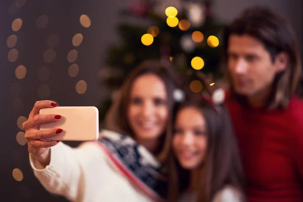 Hermosa familia celebrando la Navidad en casa y tomando selfie —  Fotos de Stock