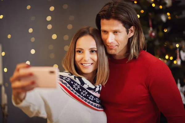 Прекрасная пара празднует Рождество дома и делает селфи — стоковое фото