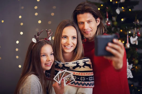 Hermosa familia celebrando la Navidad en casa y tomando fotos instantáneas — Foto de Stock