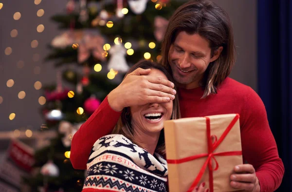 Beautiful adult couple with present over Christmas tree — Stock Photo, Image