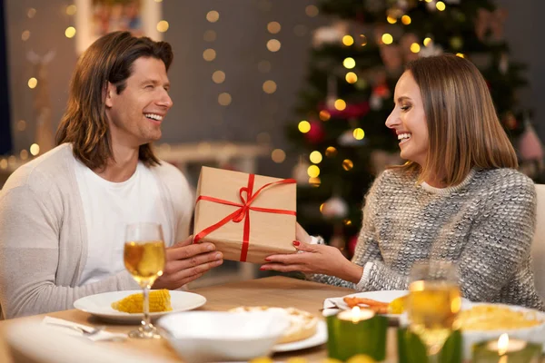 Belo casal compartilhando presentes durante o jantar de Natal — Fotografia de Stock
