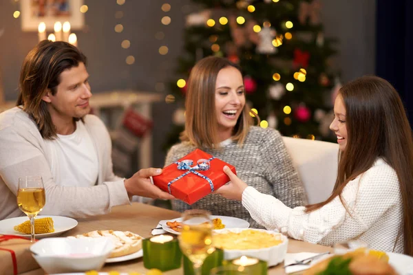 Beautiful family with presents sharing presents during Christmas dinner — Stock Photo, Image