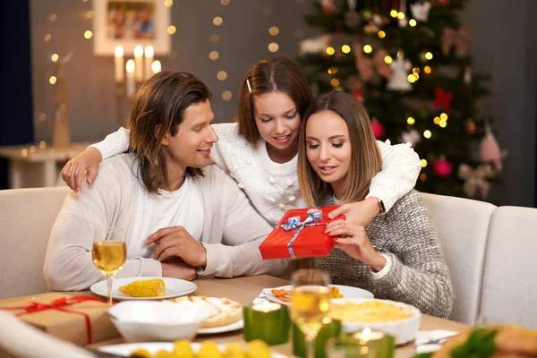 Gyönyörű család ajándékkal megosztása mutatja be karácsonyi vacsora — Stock Fotó