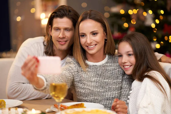 Hermosa familia celebrando la Navidad en casa y tomando selfie — Foto de Stock