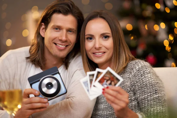 Прекрасная пара празднует Рождество дома и делает мгновенные фотографии — стоковое фото