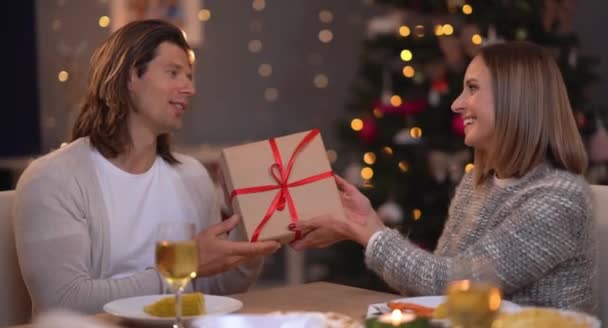 Hermosa pareja adulta con regalo sobre el árbol de Navidad — Vídeos de Stock