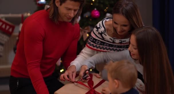 Hermosos regalos de apertura familiar sobre el árbol de Navidad — Vídeo de stock