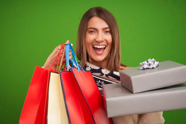 Volwassen gelukkige vrouw winkelen voor Kerstmis presenteert over groene achtergrond — Stockfoto