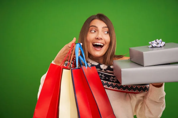 Adult happy woman shopping for Christmas presents over green background — Stock Photo, Image
