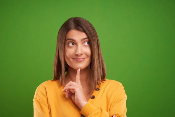 Close up de mulher em suéter amarelo pensando e apontando sobre fundo verde — Fotografia de Stock