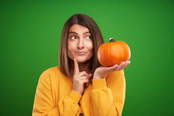 Primo piano della donna in maglione giallo che tiene la zucca su sfondo verde — Foto Stock