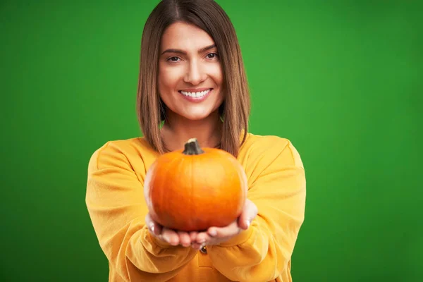 Close up de mulher em suéter amarelo segurando abóbora sobre fundo verde — Fotografia de Stock