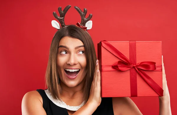 Erwachsene glückliche Frau mit Weihnachtsgeschenk auf rotem Hintergrund — Stockfoto