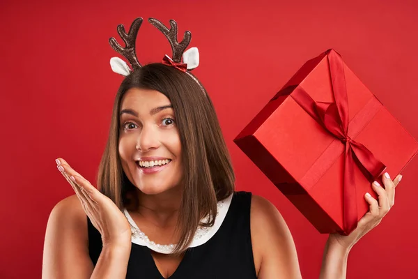 Доросла щаслива жінка з різдвяним подарунком на червоному тлі — стокове фото