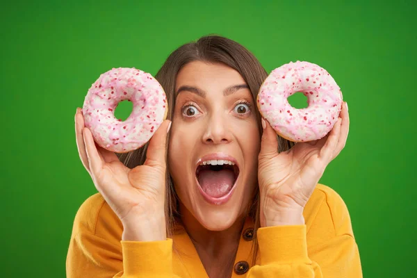 Mooie vrouw poseren met donuts over groene achtergrond — Stockfoto