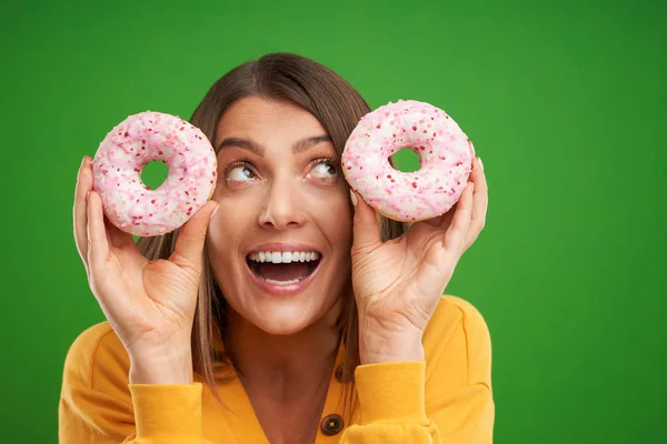 Vacker kvinna poserar med munkar över grön bakgrund — Stockfoto