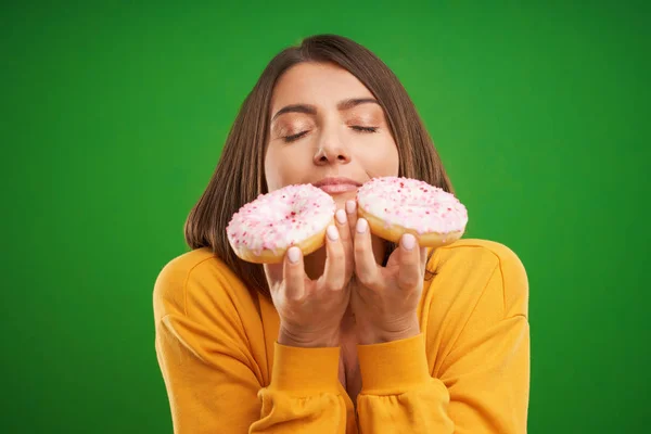 Красива жінка позує з пончиками на зеленому тлі — стокове фото