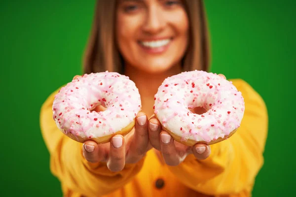 Schöne Frau posiert mit Donuts auf grünem Hintergrund — Stockfoto