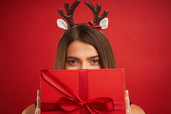 Erwachsene glückliche Frau mit Weihnachtsgeschenk auf rotem Hintergrund — Stockfoto