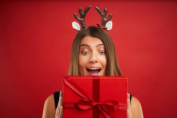 赤い背景の上にクリスマスプレゼントを持つ大人の幸せな女性 — ストック写真