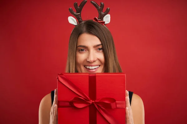 赤い背景の上にクリスマスプレゼントを持つ大人の幸せな女性 — ストック写真