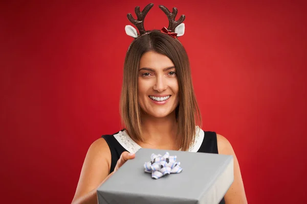 Erwachsene glückliche Frau mit Weihnachtsgeschenk auf rotem Hintergrund — Stockfoto