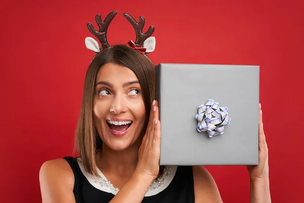 Erwachsene glückliche Frau mit Weihnachtsgeschenk auf rotem Hintergrund — Stockfoto