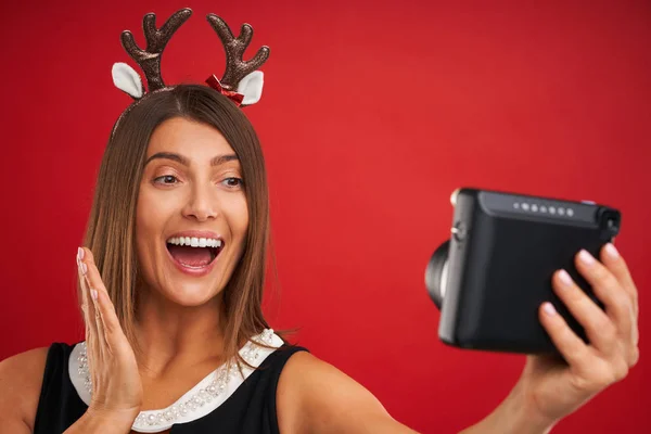 Vuxen lycklig kvinna i julstämning med omedelbar bilder över röd bakgrund — Stockfoto