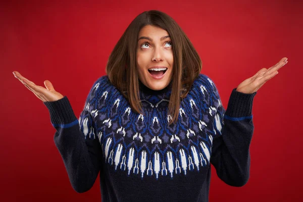 Nahaufnahme einer Frau im Weihnachtspullover, die über roten Hintergrund zeigt — Stockfoto