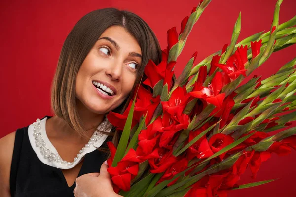 Mulher adulta com flores sobre fundo vermelho — Fotografia de Stock