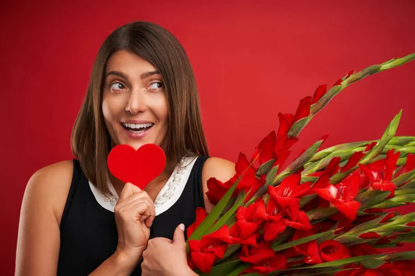 Mulher adulta com flores e coração vermelho sobre fundo vermelho — Fotografia de Stock