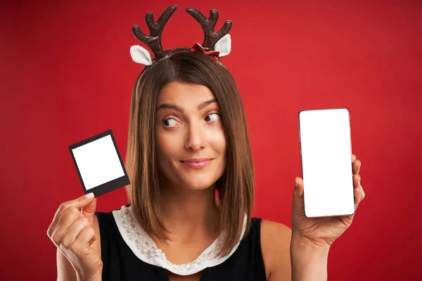 Donna in vena di Natale confrontando le immagini istantanee alla fotocamera dello smartphone su rosso — Foto Stock