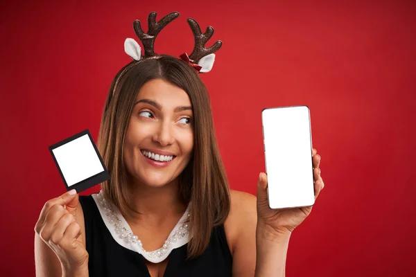 Donna in vena di Natale confrontando le immagini istantanee alla fotocamera dello smartphone su rosso — Foto Stock