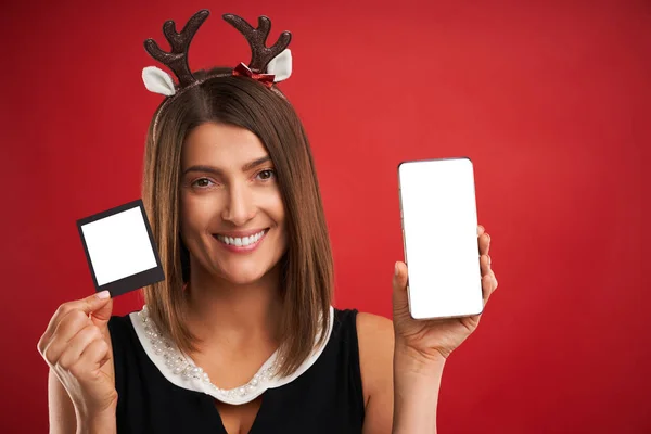 Donna in vena di Natale confrontando le immagini istantanee alla fotocamera dello smartphone su rosso — Foto Stock