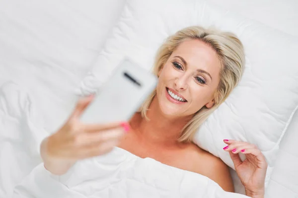 Volwassen mooie vrouw wakker volledig uitgerust en met behulp van smartphone — Stockfoto