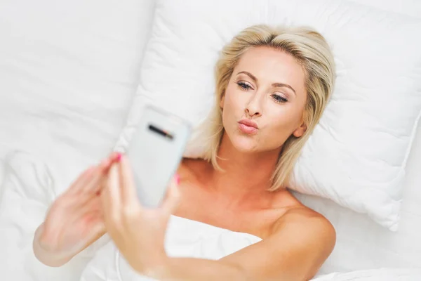Доросла красива жінка прокидається повністю відпочиває і використовує смартфон — стокове фото