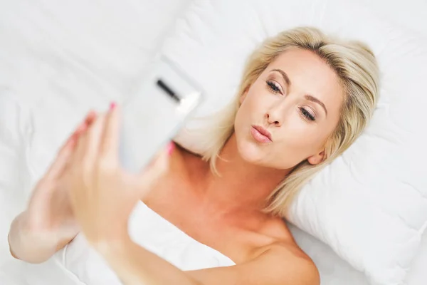 Adulto bela mulher acordar totalmente descansado e usando smartphone — Fotografia de Stock