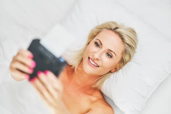 Volwassen mooie vrouw het nemen van instant foto in bed — Stockfoto