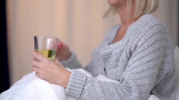 Erwachsene kranke Frau überprüft Temperatur und hält Medikamente in der Hand — Stockvideo