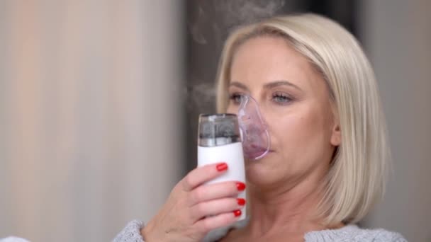 Zieke vrouw op de bank thuis inhaleert via een inhalator — Stockvideo