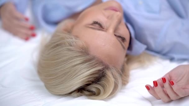 Взрослая женщина отдыхает в постели по утрам — стоковое видео