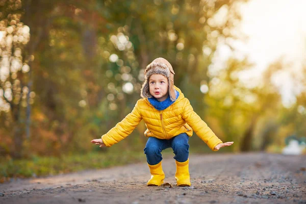 Счастливый мальчик, играющий на улице осенью — стоковое фото